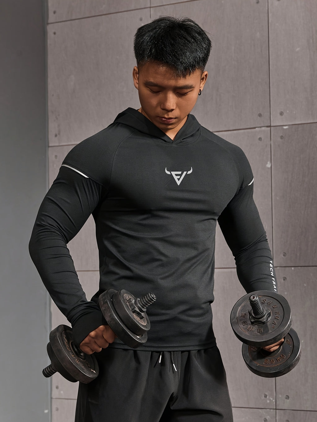 Haut d’entraînement homme à capuche, manches longues slim-fit avec passages pour pouces, tissu respirant et léger, idéal pour course et musculation.