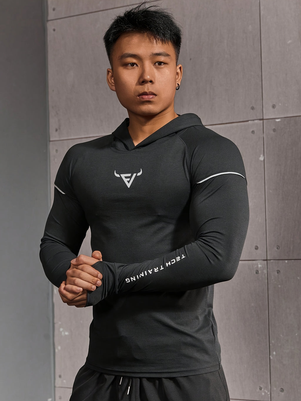 Haut d’entraînement homme à capuche, manches longues slim-fit avec passages pour pouces, tissu respirant et léger, idéal pour course et musculation.