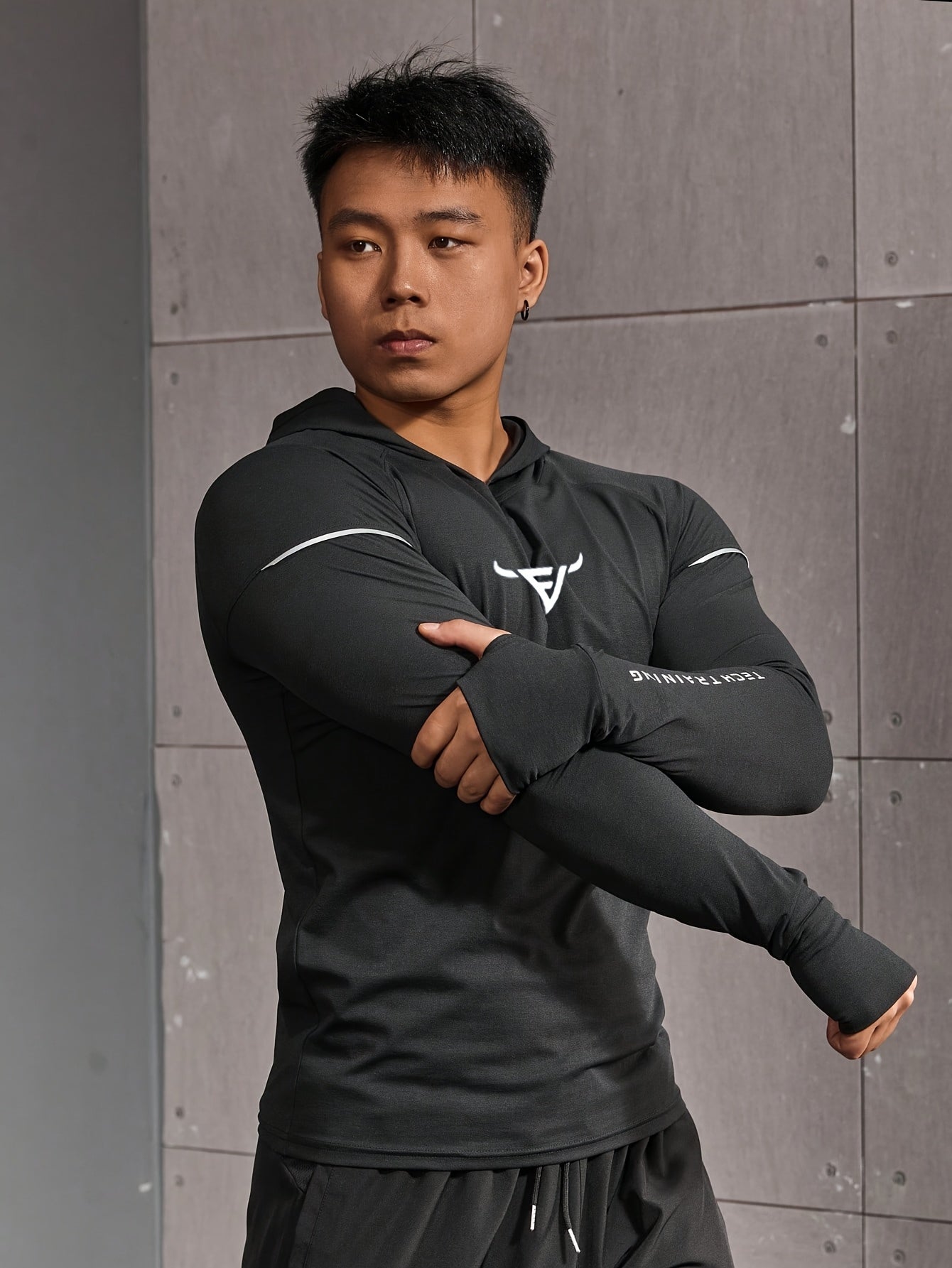 Haut d’entraînement homme à capuche, manches longues slim-fit avec passages pour pouces, tissu respirant et léger, idéal pour course et musculation.