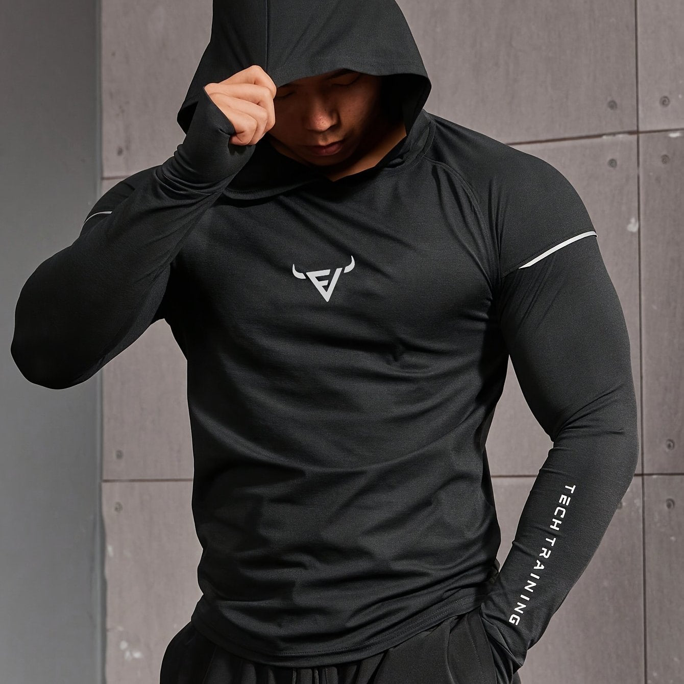 Haut d’entraînement homme à capuche, manches longues slim-fit avec passages pour pouces, tissu respirant et léger, idéal pour course et musculation.